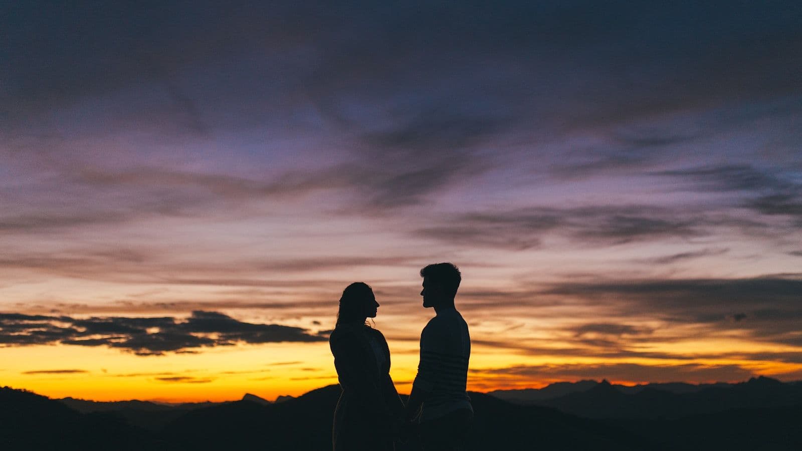 צללית זוג עומד על הר בשקיעה — אהבת אמת